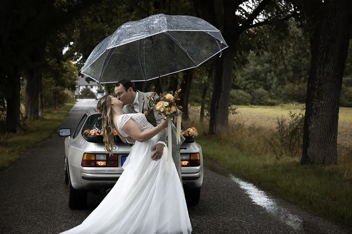 Brautpaar küsst sich unter einem Regenschirm – Hochzeitsreportage