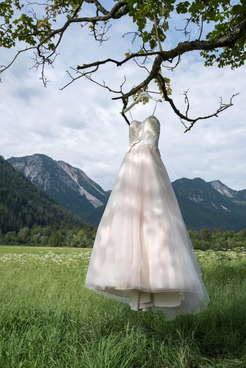 hochzeitsfotograf lichtet brautkleid vor bergen und blauem himmel ab